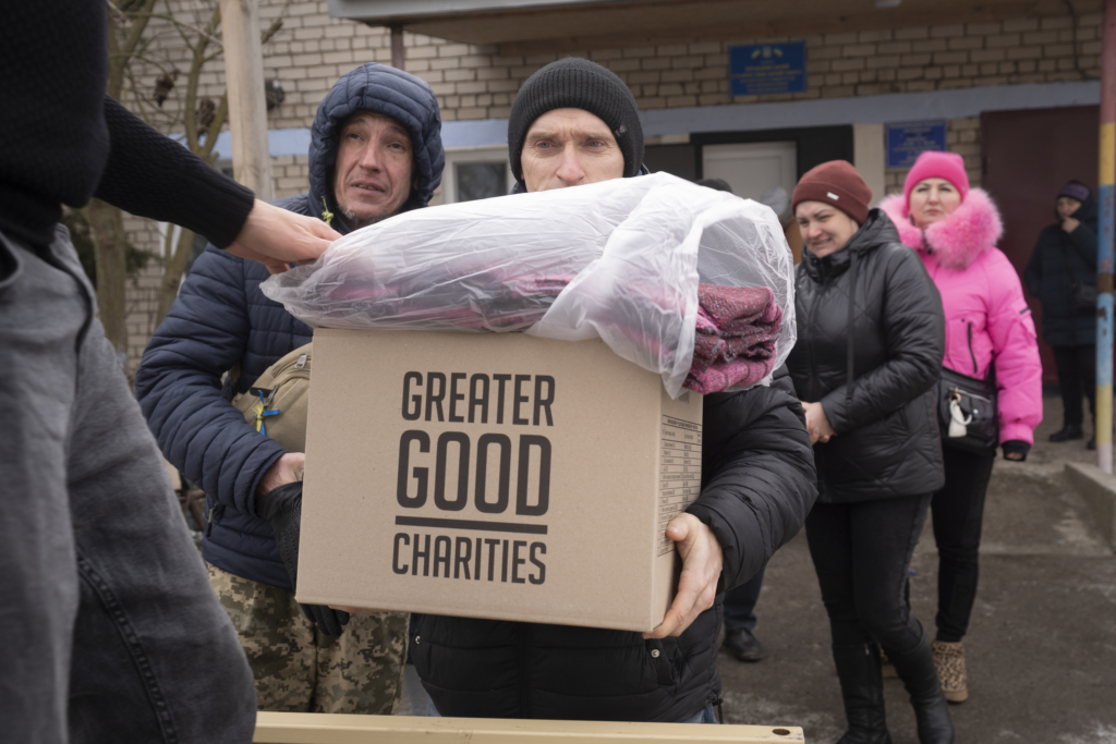 Man holding a box and a blanket from an aid distribution from Greater Good Charities in Ukraine in winter